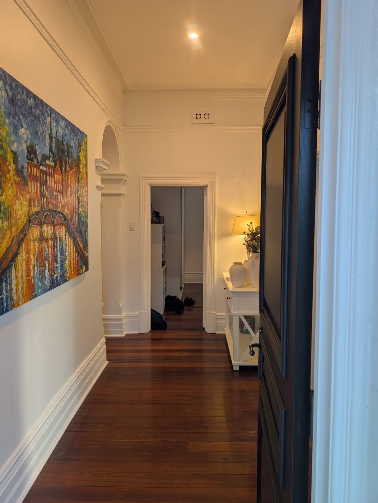 Painted heritage hallway with ornate cornices and dark feature door